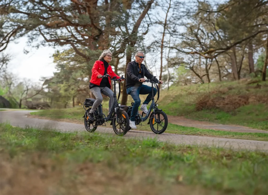 Een man en vrouw aan het fietsen op een vouwfiets Opmaet in het bos