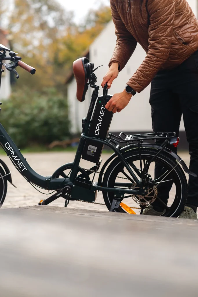 Meneer die de accu verwijderd uit een Opmaet vouwfiets